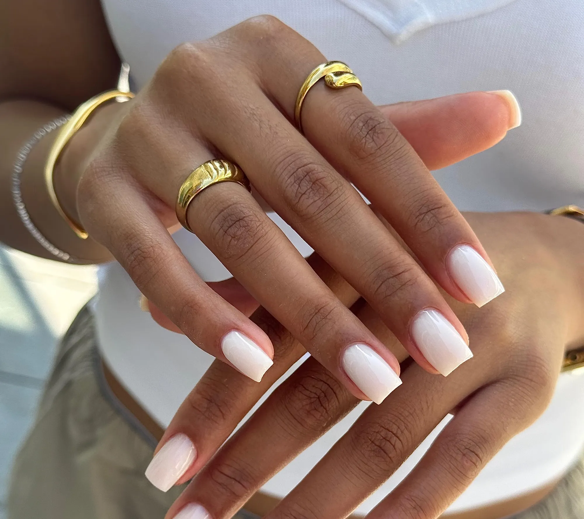 Melkwitte nagels en gouden ringen