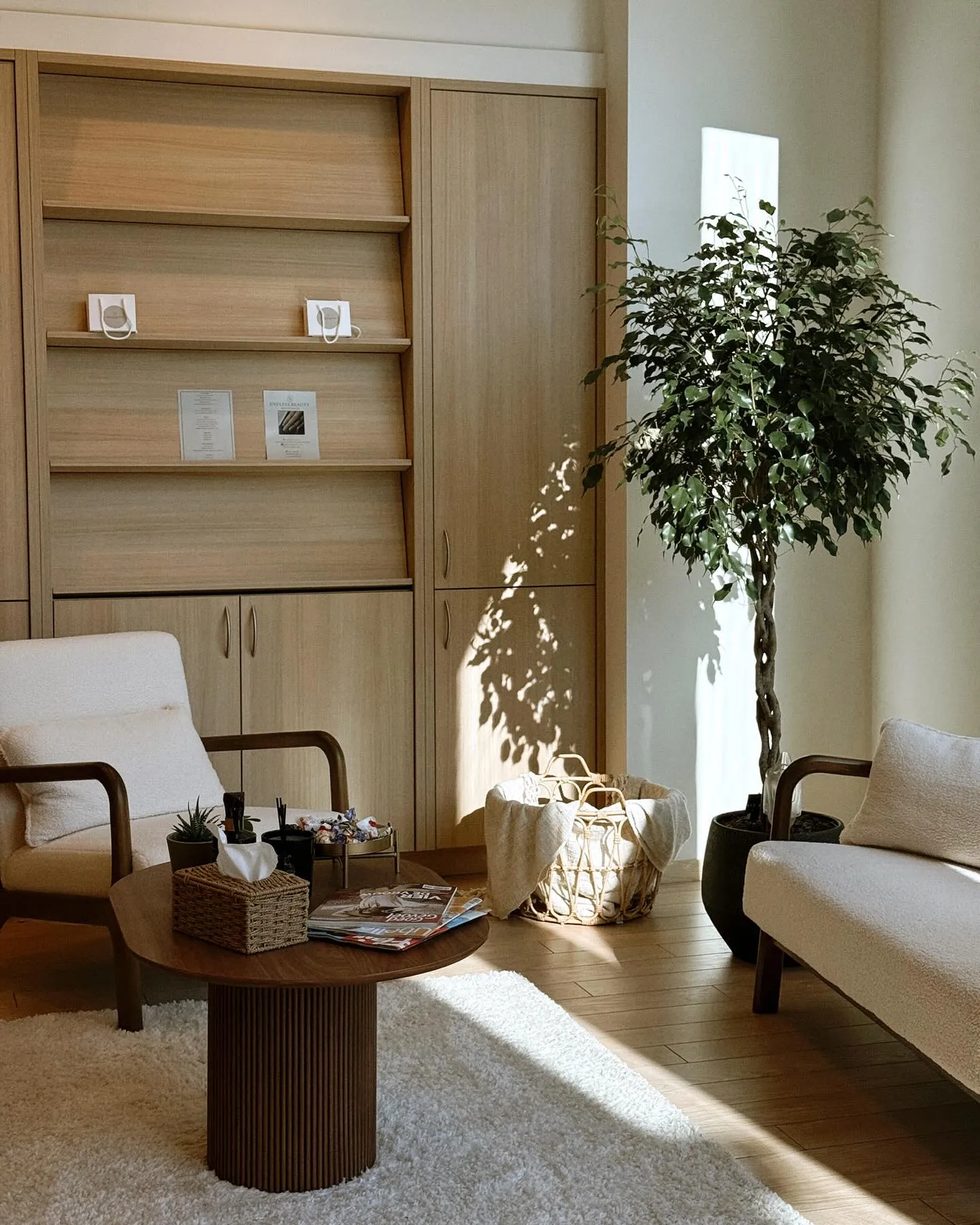 Het lichte interieur van Endless Beauty met zetels, een plant en houten kasten