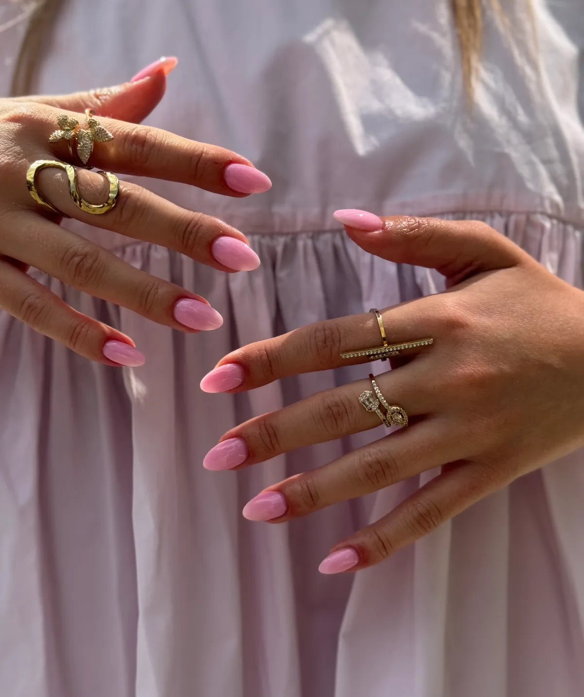 Roze amandelnagels met gouden ringen